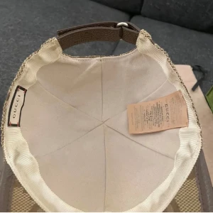 Gucci jumbo keps - Snygg beige keps från Gucci med klassiskt GG-monogram i brunt över hela kepsen. Justerbar rem baktill i brunt skinn och detaljer i canvas. Perfekt accessoar för dig som vill sticka ut med lyxig streetstyle. Kvitto finns ÄKTA SÅKLART