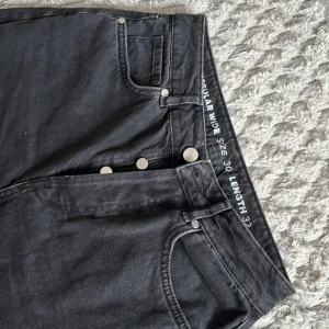 Svarta wide jeans från Bik Bok - Svarta jeans från Bik Bok i regular wide-modell med hög midja och raka, vida ben. Klassisk femficksdesign, knäppning med silverfärgade knappar och tillverkade i denim. Perfekta för en avslappnad och trendig look.