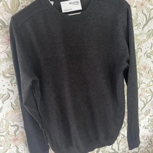 Mörkgrå tröja från Selected Homme - En stilren mörkgrå tröja från Selected Homme i klassisk modell. Tröjan har rund halsringning, långa ärmar och ribbade muddar vid ärmslut och nederkant. Tröjan är riktigt underbar att ha på en sommar kväll då den är ganska tunn och mjuk (stickad)