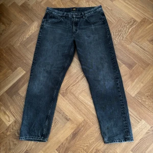 Svarta jeans från Lee, modell Oscar - Säljer ett par svarta jeans från Lee i modellen Oscar. Jeansen har klassisk femficksdesign, raka ben och normal passform. Materialet är slitstarkt denim i bomull och färgen är tvättad svart med en lite vintage känsla.