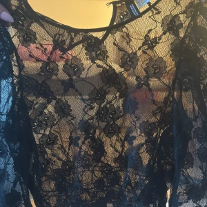 Svart spetsblus med blommönster -  svart spetsblus från H&M med blommönster. Storlek 34, säljer för 75