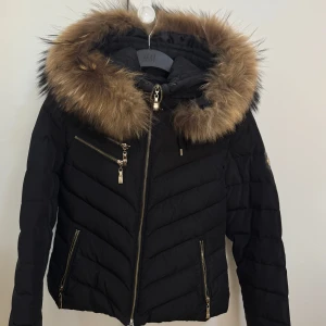 Svart hollies jacka med äkta päls  - Snygg svart dunjacka från hollies med äkta päls. Storlek 34 