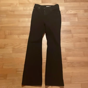 Svarta bootcut jeans från Levi's - Snygga svarta bootcut jeans från Levi's med klassisk design. De har en dragkedja och knappar framtill samt fem fickor. Perfekta för en stilren look.