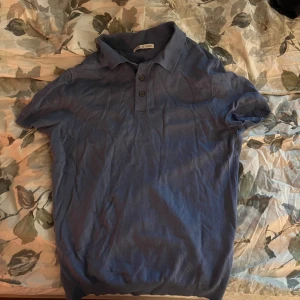 Blå pikétröja från Zara  - Snygg blå pikétröja från Zara med korta ärmar och tre knappar vid halsen. Perfekt för en stilren och avslappnad look. Passar bra till både jeans och chinos.