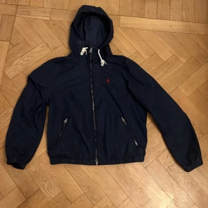 Polo Ralph Lauren vind jacka - Polo Ralph Lauren vind jacka i ny skick. Jackan är rätt så gammal men funkar fortfarande perfekt förutom att dragkedjan ibland kan vara jobbig att dra igen. Jackan har inga defekter. Storleken är S men jackan har en croppad look och sitter mer som XS. Passar någon från ungefär 165-170.
