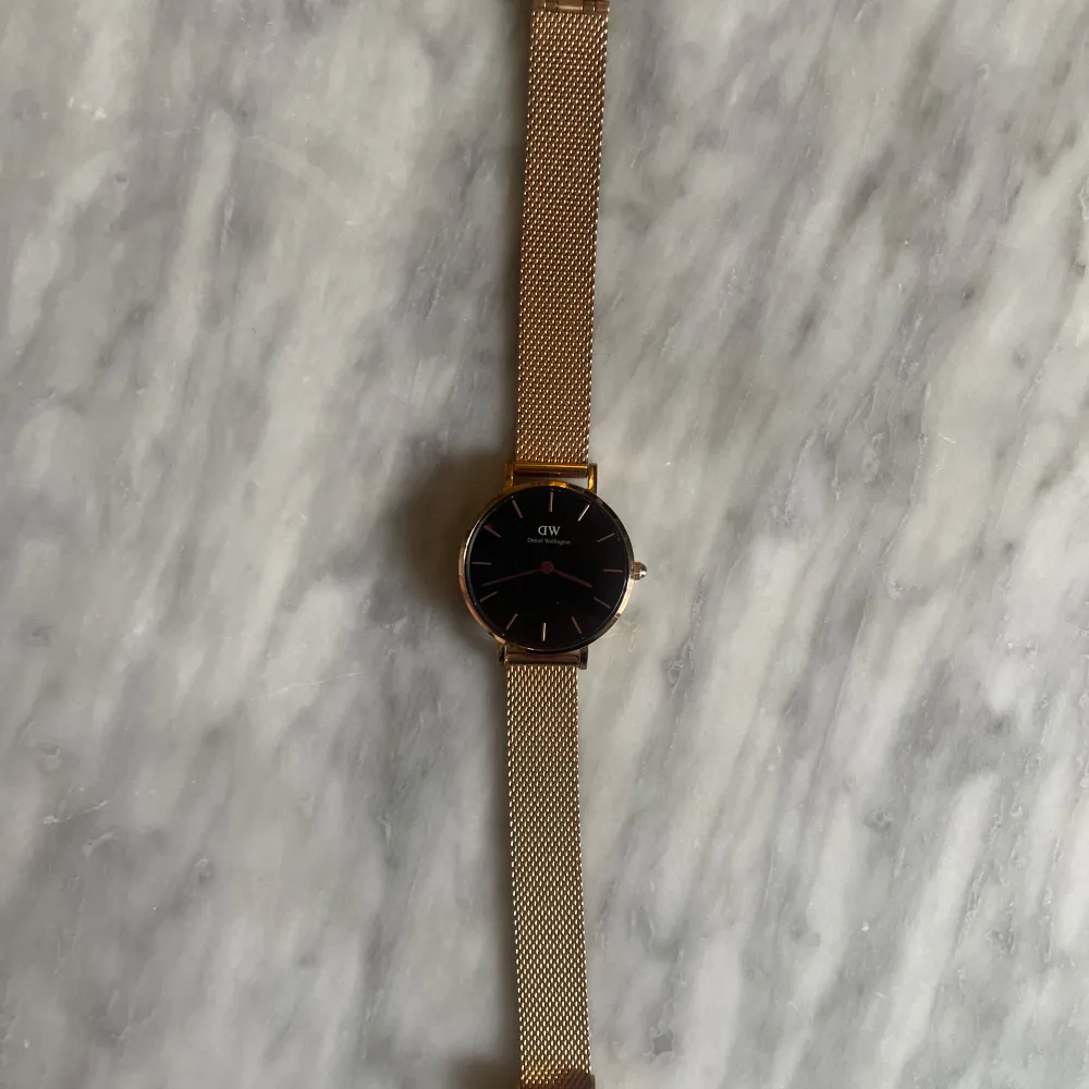 Petite Pressed Melrose klocka från Daniel Wellington. Klockan är tillverkad i polerat rostfritt stål och har en plätering i roséguld. Svart urtavla. 24 mm. . Asusteet.