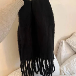 Svart halsduk med fransar - Snygg marinblå halsduk med långa fransar som ger en cool look. Perfekt för att hålla sig varm under kyliga dagar. Passar bra till både jackor och kappor.