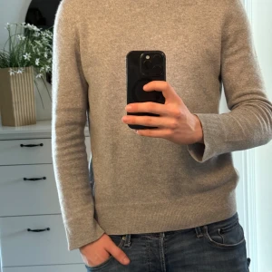 Grå kashmirtröja - Säljer en stilren och mjuk grå tröja i 100% kashmir. Perfekt för kyliga dagar med sin långärmade design och klassiska look. Passar både till jeans och mer uppklädda tillfällen.