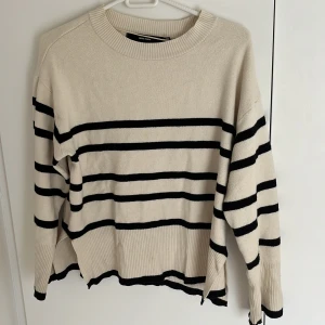 Beige och svart randig tröja - Säljer en snygg beige tröja med svarta ränder från Vero Moda. Tröjan har en avslappnad passform med långa ärmar och ribbade kanter. Perfekt för en stilren look! Har supersmå fläckar som knappt syns. Kontakta vid frågor❤️❤️