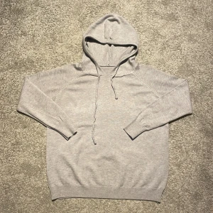 Grå merinoull hoodie - Säljer denna oanvända merinull hoodie pga att den är för liten. Väldigt trändig och stilren tröja med ett exklusiv material.