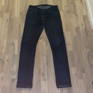 Nudie jeans - Snygga mörkblå jeans från Nudie. De har en slim passform och är tillverkade i högkvalitativt denim. Perfekta för en stilren look. Skicket är 9/10 i storlek 31W och 34L. Skriv vid minsta fundering😁🔛🔝
