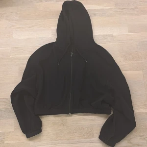 Svart croppad hoodie från Lager 157 - Säljer en svart croppad hoodie från 157. Den har en dragkedja framtill och en mysig huva. 