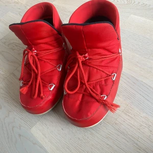 Röda Moon Boots med snörning - Snygga röda Moon Boots med snörning och vit sula. Perfekta för vintern med sin varma och vadderade design. 