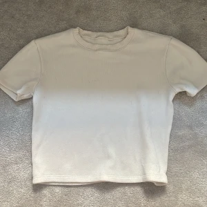 Zara topp - Säljer en vit ribbad topp från Zara med korta ärmar. Perfekt för en enkel och fräsch look. Toppen har en rund halsrigning. 