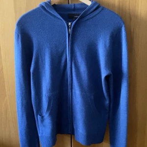 Merinoull hoodie med zip - Säljer en snygg blå hoodie med dragkedja och huva. Tröjan har långa ärmar och praktiska fickor framtill. Perfekt för en avslappnad stil. Tröjan är gjort i merinoull som är väldigt skönt och stilrent material. Tveka inte på att ställa frågor🤙🏼priset går att diskutera 