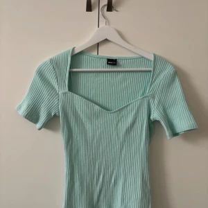 Mintgrön ribbad topp från Gina Tricot - Säljer en mintgrön ribbad topp från Gina Tricot i storlek XS. Toppen har korta ärmar och en v-ringad design som ger en stilren look. Perfekt för en fräsch och somrig stil. Hör av dig vid intresse! 🌿