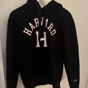 Svart hoodie från Champion med Harvard-tryck - Säljer en svart vintage  hoodie från Champion med Harvard-tryck i vitt och rött. Tröjan har en klassisk passform med långa ärmar och en bekväm huva med dragsko. Perfekt för en avslappnad stil. 🖤Passar även XS!!