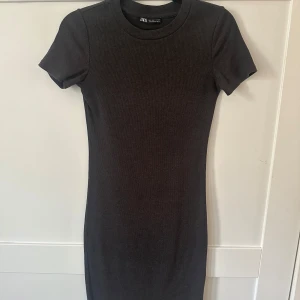 Svart ribbad klänning från Zara - En superfin tight och stretchig mörkgrå klänning från Zara i storlek S. Den slutar strax över knäna på mig som är 175. Använd mycket men sparsamt. Sitter super snyggt på✨