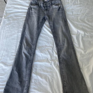 Grå bootcut jeans från Gina Tricot - Snygga grå bootcut jeans från Gina Tricot i storlek 158. Jeansen har en klassisk femficksdesign med dekorativa sömmar på bakfickorna. Perfekta för en avslappnad stil med en touch av retro.
