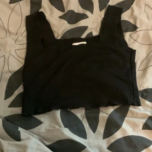 Svart croppad topp från H&M - Säljer en svart croppad topp från H&M. Toppen är ärmlös och har en stilren design. Perfekt för att matcha med höga jeans eller kjol. Tillverkad i en mjuk och stretchig blandning av viskos och polyamid.