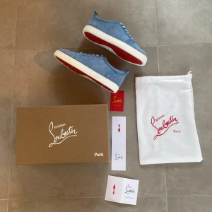 Blå sneakers från Christian Louboutin - Snygga blå sneakers från Christian Louboutin i mocka med den ikoniska röda sulan. Skorna har snörning och en stilren design som passar perfekt för en trendig look. Levereras med originalförpackning och dustbag. Bara att ställa frågor om funderingar.
