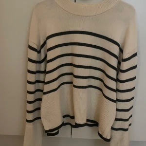 Randig tröja från Gina Tricot - Säljer en snygg randig tröja från Gina Tricot i beige och svart. Tröjan har långa ärmar och en rund halsringning. Perfekt för en stilren look. Passar bra till både jeans och kjol!