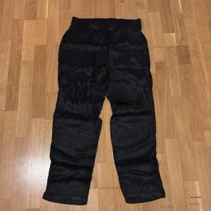 Svarta silkes byxor  - Svarta silkesbyxor perfekt för varma dagar Byxorna har en elastisk midja för extra komfort. Helt oanvända! 