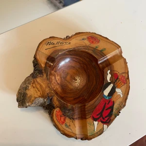 Askkopp i trä från Mallorca - Unik vintage handgjord trä askkopp med en vacker målning av en traditionell dansare och blommor. Skålen har en naturlig träfinish och är märkt med 'Mallorca'.kan möta er i Stockholm utanför Åhléns 
