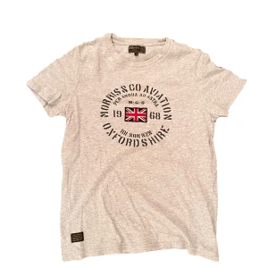 Grå t-shirt från Morris - Snygg grå t-shirt från Morris med tryck av Union Jack och texten 'Morris & Co Aviator Oxfordshire'. Perfekt för en avslappnad stil. Tillverkad i mjukt bomullsmaterial.