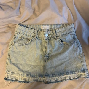 Jeanskjol - Snygg oanvänd jeanskjol från Pull&Bear i ljusblå denim. Kjolen har en klassisk femficksdesign och rå kant nedtill för en trendig look. Perfekt för en avslappnad stil. Pris diskuterbart vid snabb affär💕 