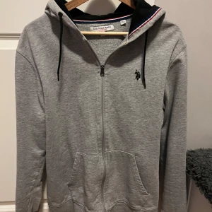 US Polo Assn tröja - Säljer en grå hoodie från US Polo Assn. Tröjan passar mig inte längre och har mest hängt i garderoben. Nypris-700kr