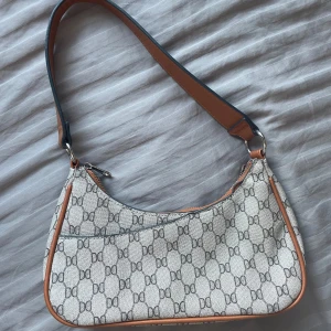 Mönstrad axelväska med bruna detaljer - Axelväska från Don Donna i jättefint skick!