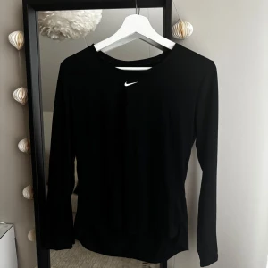 Svart långärmad tröja från Nike - Säljer en stilren svart långärmad tröja från Nike. Perfekt för träning eller vardagsbruk. Tröjan har en enkel design med en liten Nike-logga på bröstet. Passar bra till olika outfits och aktiviteter.