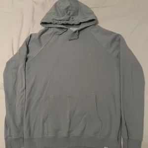  hoodie från Les Deux - Säljer en stilren turkos hoodie från Les Deux. Den har en klassisk design med en stor ficka framtill och justerbar huva. Perfekt för en avslappnad look. Den är i fint skick utan skador och defekter. Den är i storlek L
