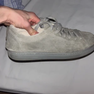 Grå mockasneakers - Snygga grå sneakers i mocka med snörning. Perfekta för en stilren och avslappnad look. Skorna har en klassisk design med rund tå och en bekväm sula från selected homme. 