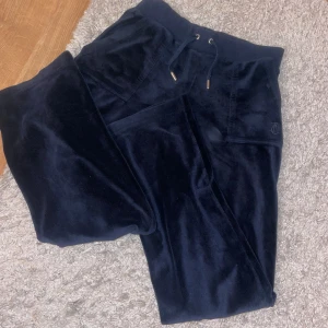 Mörkblå velourbyxor från Juicy Couture -  mörkblå velourbyxor från Juicy Couture med elastisk midja och snörning. Byxorna har två bakfickor med knappar och  broderad logga på sidan. Använd fåtal gånger så dem är i väldigt bra skick 🟥pris kan diskuteras🟥 skriv om ni vill ha flera bilder 