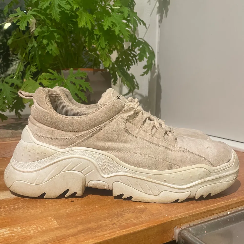 Säljer ett par chunky beige sneakers från NA-KD. Skorna har en tjock sula och ger lite extra längd!. Kengät.