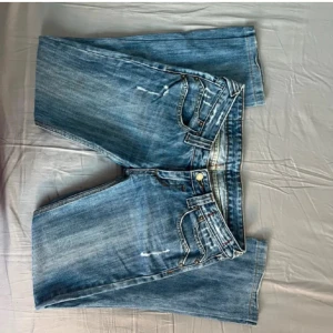 Blå jeans med detaljer - Bilderna är från hon jag köpte de av men de passade inte mig. Snygga blå jeans med slitna detaljer och dekorativa sömmar på bakfickorna. Sprättat upp längst ner på byxorna för de var korta men inget som syns på. Är 165 o de va lite korta, ganska hårt matrial