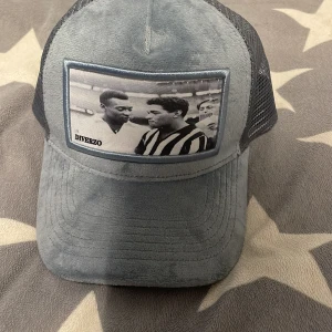 Grå keps med fototryck från Diverzo - Snygg grå keps från Diverzo med ett coolt fototryck på framsidan. Kepsen har ett nätmaterial baktill för bättre ventilation och justerbar passform. Perfekt för en avslappnad stil.