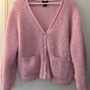 Rosa stickad kofta från Lindex - Mysig rosa stickad kofta från Lindex med v-ringning och knappar framtill. Säljs då den inte kommer till användning längre. 