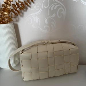 Axelväska med flätad design - Snygg axelväska som är helt ny. Väskan har en justerbar axelrem och en praktisk dragkedja upptill 🤍