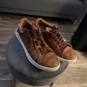 Snygga bruna sneakers i skinn från Polo Ralph Lauren med vit sula.  slitna men inte några direkt skador. 