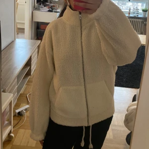Vit vårjacja med dragkedja - Mysig vit jacka med dragkedja och hög krage. Jackan har en avslappnad passform och stora fickor framtill💕