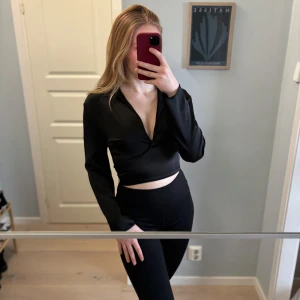 Svart omlottopp i silke - Svart silkes topp, använd ett fåtal gånger, omlott med rosett i ryggen 