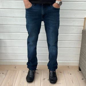 Mörkblå jeans från Lee - Snygga mörkblå jeans från Lee modellen rider med klassisk femficksdesign och Lee-logga bak i midjan. Jeansen har rak passform och är tillverkade i mjukt denimtyg. Perfekta för dig som gillar en tidlös och clean look.