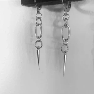 Silvriga örhängen med kedjor och spikes - Säljer ett par coola silvriga örhängen med kedjelänkar och spetsiga spikes längst ner. De har en edgy vibe och passar perfekt för dig som gillar statement-smycken. Lätta att bära och ger en snygg touch till din stil.