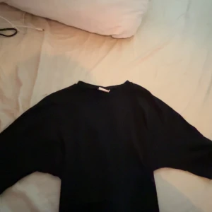 Svart långärmad tröja från Nelly - Enkel svart långärmad tröja från Nelly i storlek XS.  Med knyt där bak. Andvänd men inte synligt