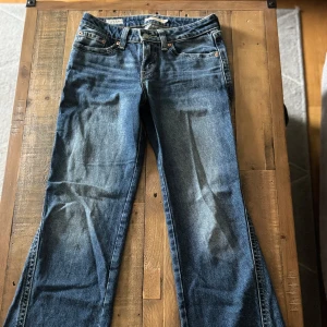Levi's 517 bootcut jeans blå denim - Säljer ett par klassiska Levi's 517 jeans i blå denim med bootcut passform. Jeansen har fem fickor, snygga kontrastsömmar och typisk Levi's-detalj på bakfickan. Perfekta för dig som gillar retrovibbar och en avslappnad stil.
