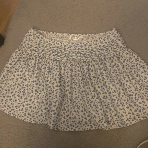 Blommig kortkjol  - Supersöt kort kjol från Gina Young med blått blomm mönster. Använd 2 gånger