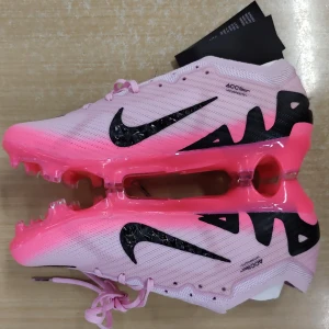 Nike Mercurial rosa fotbollsskor - Nike Mercurial fotbollsskor i en snygg rosa färg med svarta detaljer och logga. Skorna har snörning, platt sula med dobbar och är tillverkade i syntetmaterial för bästa grepp och lätt känsla på planen. Perfekta för dig som vill sticka ut på fotbollsplanen.